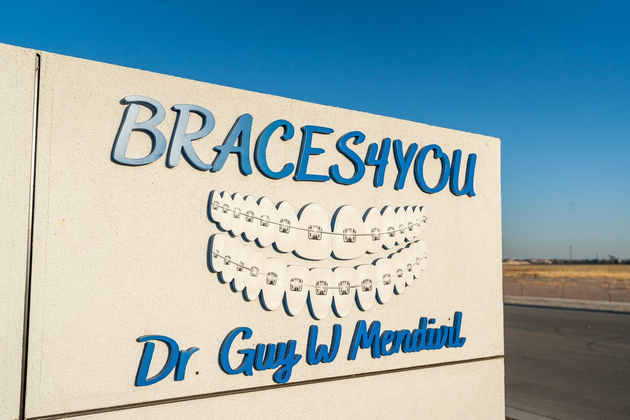 Dr. Mendivil Orthodontics logo on a stone wall at the building entrance