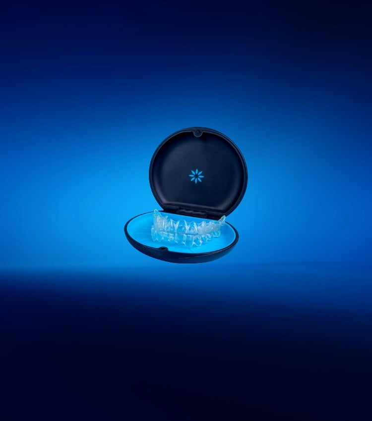 Clear aligner tray inside an open black case against a blue background